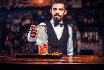 Bearded bartender makes a cocktail on the bar