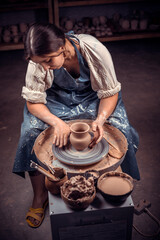 Stylish handicraftsman master making pottery, sculptor from wet clay on wheel. Artisan production.