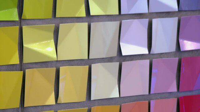 Wall with hanging colored square metal pieces of the same size.