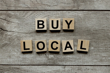 Buy local, text on wooden blocks on a wooden background
