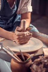 The potter works in the workshop. Hands and a potter's wheel close-up