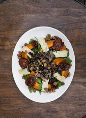 Gourmet salad. Top view of a gourmet salad with arugula, roasted pumpkin, almonds, brie cheese, sun dried tomatoes and mushrooms.