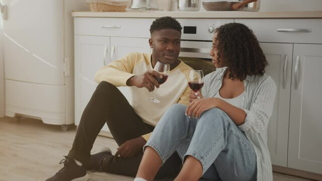 Zoom in portrait of young talkative african american man and woman talking to each other, discussing day with red wine