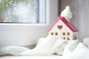 Cozy house is wrapped in a hat and scarf in a snowstorm -window sill decor. Winter, snow - home...