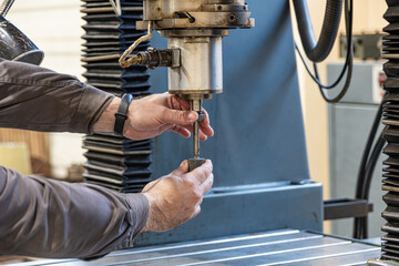 The worker changes the grinding wheel on the mandrel of the cylindrical grinder.