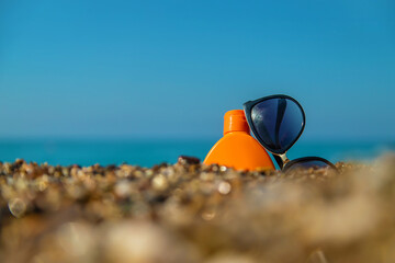 Sunscreen and glasses on the beach. Selective focus.