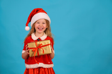 fun child in Santa hat hold gift Happy merry Christmas. beautiful girl smiles laughs. Congratulate celebration. Jolly Santa Claus preparing box gold bow. Happy New Year. Place for text. Copy space. 