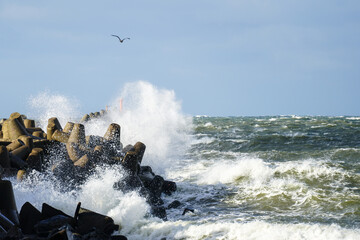 during stormy weather, large waves crash against the concrete blocks of a breakwater
