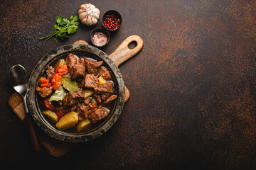 Delicious beef meat stew dish with potatoes, carrot and gravy in rustic metal bowl with spoon,...