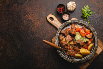 Delicious beef meat stew dish with potatoes, carrot and gravy in rustic metal bowl with spoon,...