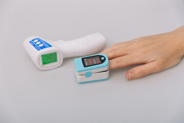 Pulse oximeter and thermometer gun on white background. Measuring oxygen saturation, pulse rate and...