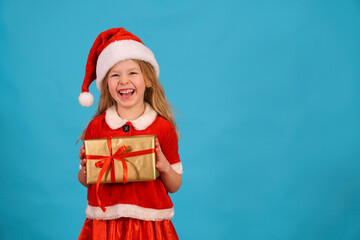 fun child in Santa hat hold gift Happy merry Christmas. beautiful girl smiles laughs. Congratulate celebration. Jolly Santa Claus preparing box gold bow. Happy New Year. Place for text. Copy space. 