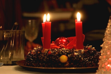 Advent wreath with four lit candles and Christmas decoration on a holiday table. Selective focus.