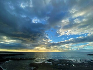 Beautiful sunset over the ocean with dramatic clouds and blue sky