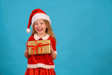 Happy merry Christmas child in Santa hat hold gift. beautiful girl smiles laughs. Congratulate celebration. Jolly Santa Claus preparing box gold red bow. Happy New Year. Place for text. Copy space. 