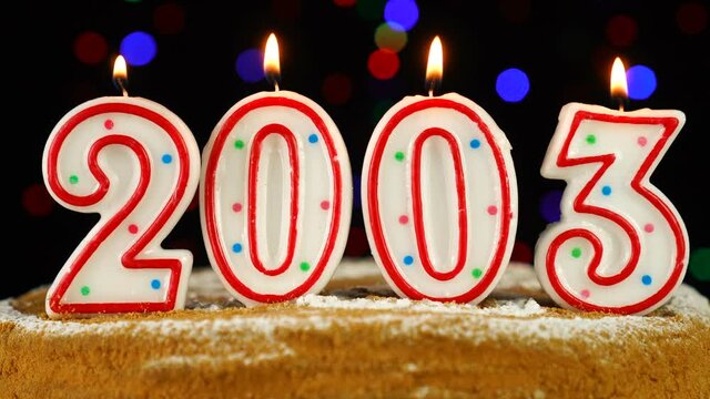 Birthday cake with white burning candles in the form of number 2003