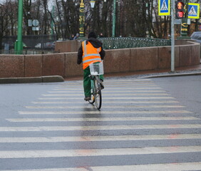 Obraz premium A worker in an orange vest on a bicycle violates traffic rules, Moika River embankment, St. Petersburg, Russia, November 2021