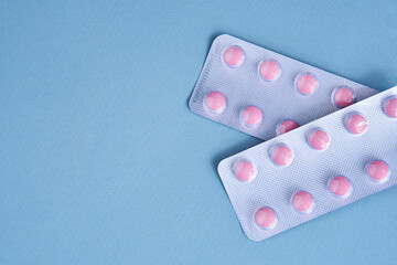 pink pills in packs vitamins pain reliever blue background