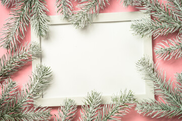 Christmas composition with photo frame and fir tree branch at pink background. Flat lay image with...