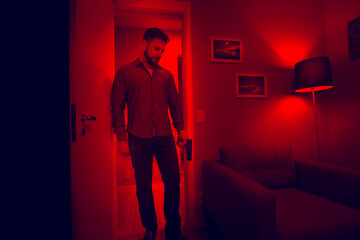 Armed man entering a mysterious dark room