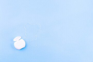 Dental floss on blue background, copy space, horizontal