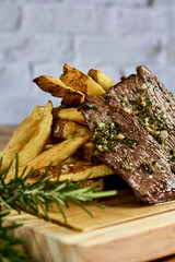 roast meat dipped in chimichurri with fries on a board