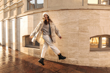 Energetic young caucasian woman posing in flight while walking through city streets. Brunette in...