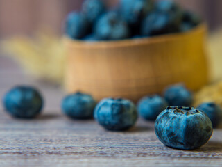 Freshly picked blueberries in a wooden bowl on a wooden background. Healthy food and nutrition. Place for text.