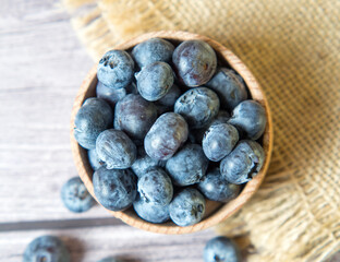 Freshly picked blueberries in a wooden bowl on a wooden background. Healthy food and nutrition. Place for text.