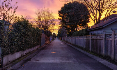 Alley in a residential neighborhood in the city suburbs. Surrey, Greater Vancouver, British Columbia, Canada. Dramatic Colorful Fall Sunrise.