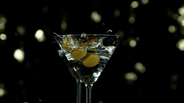 Super slow motion of falling olives into cocktail drink, camera movement. Speed ramp effect. Filmed on high speed cinema camera, 1000 fps.