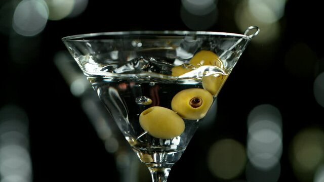 Super slow motion of falling olives into cocktail drink, camera movement. Speed ramp effect. Filmed on high speed cinema camera, 1000 fps.