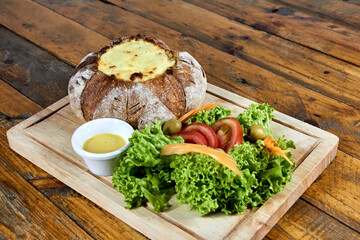 peasant bread stuffed with meat and chicken covered with cheese with salad