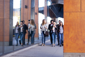 Group of people walking on a street with confidence. Businessmen and businesswomen traveling together..