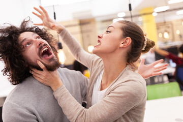 Fototapeta premium Friendly colleagues fooling around in a modern coworking office space. Lovely couple making funny face expressions.