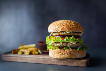 delicious large double burgeon with vegetables cutlet veal meat with lettuce and cheese on a wooden board .Hamburger with fries