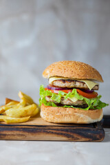 delicious large double burgeon with vegetables cutlet veal meat with lettuce and cheese on a wooden board .Hamburger with fries