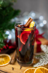 delicious hot spicy red mulled wine with orange and cinnamon spices near the Christmas tree with decorations and bokeh garlands