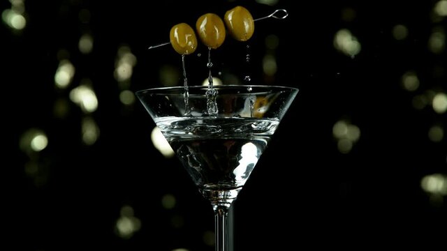 Super slow motion of falling olives into cocktail drink, camera movement. Filmed on high speed cinema camera, 1000 fps.
