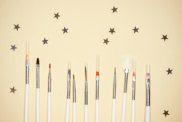 Brushes for manicure and nail design of different shapes and sizes on a beige background.