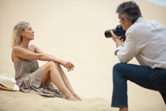 happy mature couple taking photos at the beach