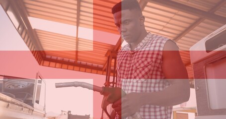 Double exposure of man holding petrol pump at gas station with england flag