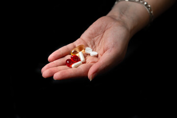 multicolored pills or vitamins are poured into the hand on a black background. High quality photo