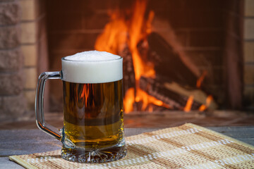 Beer glass before the cozy firepace in country house.