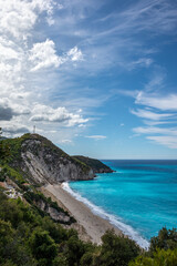 Fototapeta na wymiar Mylos sandy beach with azure vibrant stormy waves and clouds on coast of Lefkada island in Greece. Summer nature travel to Ionian Sea. Vertical