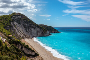 Scenic Mylos sandy beach with azure vibrant waves and green hills on coast of Lefkada island in Greece. Summer nature travel to Ionian Sea