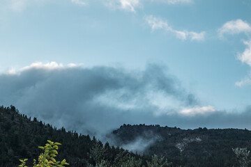 Mystic cloudy landscape on green Greek hills. Low clouds on scenic sky above dark green hills on Lefkada island, Greece