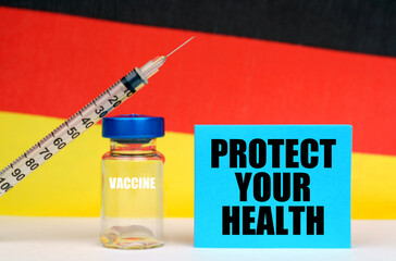 Vaccine, syringe and blue plate with the inscription - PROTECT YOUR HEALTH. In the background the flag of Germany
