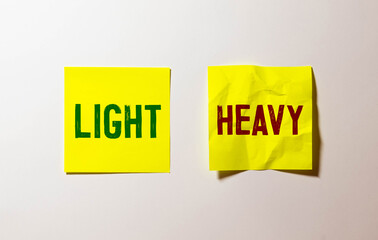 Macro photo of tooth wheel mechanism with arrows and HEAVY, LIGHT concept words.