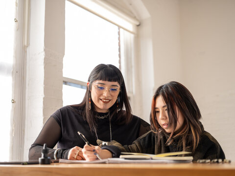 Non binary artist and non-binary student drawing indoors